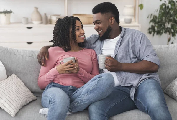 Descanso de quarentena. Casal preto romântico relaxante no sofá com café — Fotografia de Stock