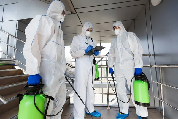 Desinfección al aire libre por trabajadores de limpieza en trajes de materiales peligrosos —  Fotos de Stock