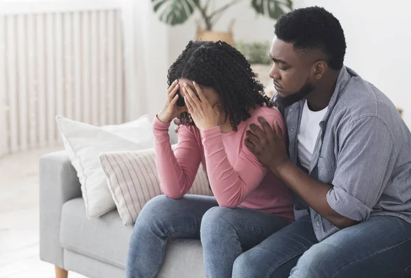 Carinhoso namorado negro confortando sua namorada chorando chateado em casa — Fotografia de Stock