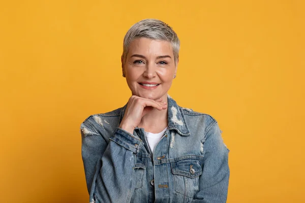 Retrato de dama madura confiada tocando la barbilla y sonriendo a la cámara —  Fotos de Stock