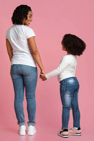 Loving Black Mom And Daughter Holding Hands And Smiling, Rear View