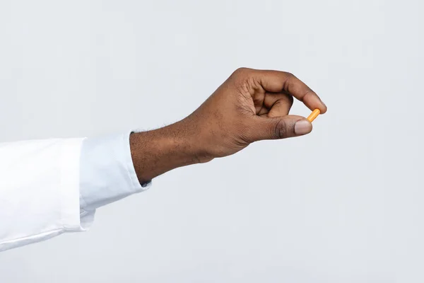 Primer plano de la mano del médico negro sosteniendo una sola píldora — Foto de Stock