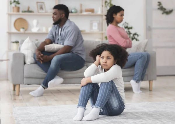 Irritado pouco preto menina sentado separadamente a partir de pais depois de seu discutir — Fotografia de Stock