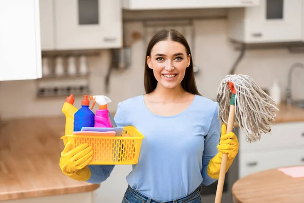 Młoda kobieta trzyma mop i wiadro z detergentami — Zdjęcie stockowe
