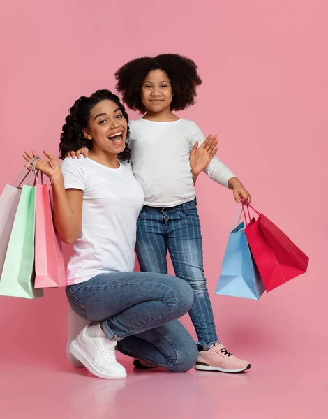 Heyecanlı Afro-Amerikalı anne ve küçük kızı alışveriş paketleriyle poz veriyorlar. — Stok fotoğraf