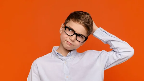 Pochybný dospívající chlapec v brýlích škrábání na hlavě — Stock fotografie