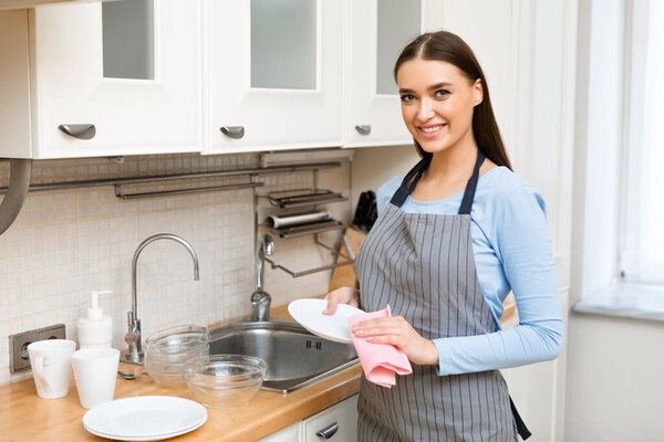 Молодая женщина вытирает посуду, вытирает ее
