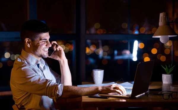 Office Manager Guy Συνομιλία στο κινητό τηλέφωνο κάθεται στο φορητό υπολογιστή εσωτερικούς χώρους — Φωτογραφία Αρχείου