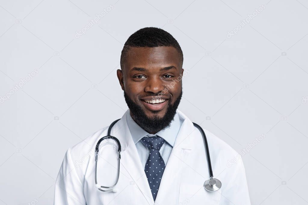 Portrait of cheerful black doctor with stethoscope on white background