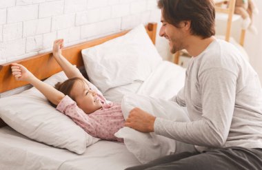 Anaokulu kızı uyandıktan sonra yatakta geriniyor.