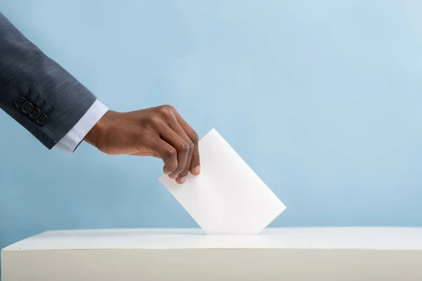 Hombre afroamericano poniendo una boleta vacía en la urna electoral — Foto de Stock