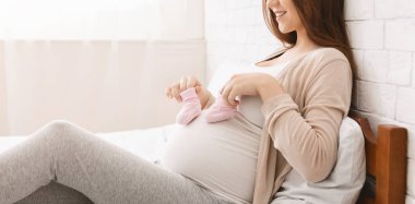 Pregnant woman playing with small booties and her belly