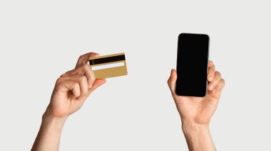 İnternetten alışveriş. Tanımlanamayan adamın elinde kredi kartı ve akıllı telefon var. Ekranı boş, tasarım için yeri var.