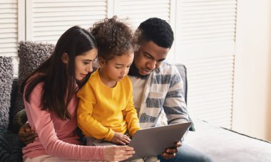 Uluslararası aile evde tablete bakıyor