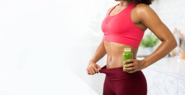 Büyük Pantolon Giyen İnce Afro Kız Detox Smoothie Tutuyor