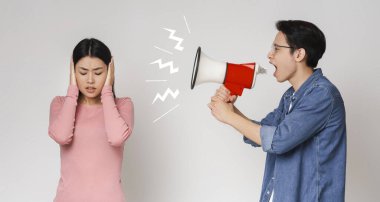 Asyalı adam hoparlör kullanarak karısına bağırıyor.