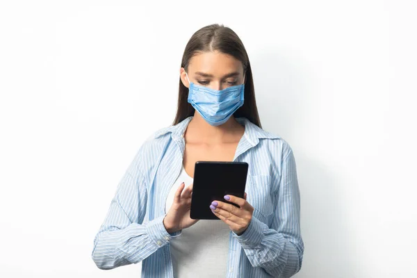 Vrouw in het gezicht masker met behulp van Tablet Computer op witte achtergrond — Stockfoto