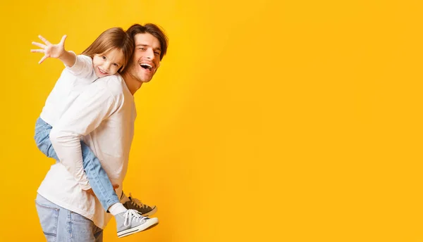 Pai positivo segurando sua filha feliz em suas costas — Fotografia de Stock