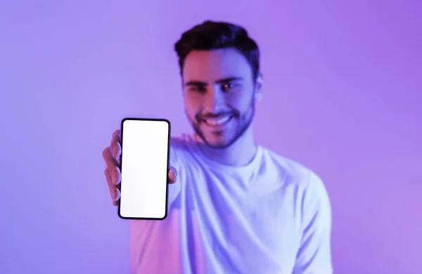 Guy in neon mostra smartphone con schermo vuoto — Foto Stock