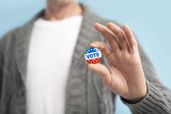 Ciudadano americano respetuoso de la ley sosteniendo pin voto en la mano —  Fotos de Stock