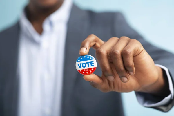 Африканский мужчина держит кнопку голосования на синем фоне — стоковое фото