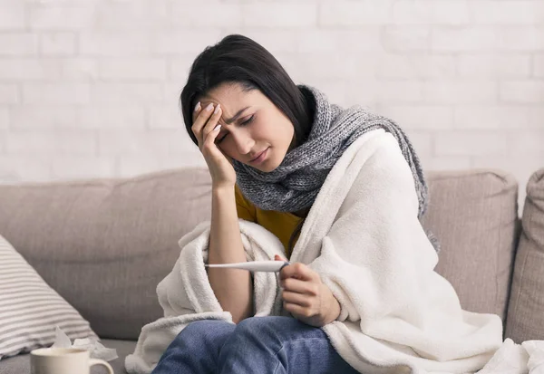 Medelsvår sjukdom. Ung flicka med hög feber och tittar på termometer hemma — Stockfoto