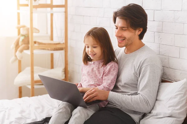 A kislány az apjával van, laptopot használ. — Stock Fotó