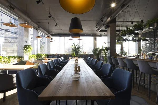 Long table for big company in cozy cafe interior, nobody indoors