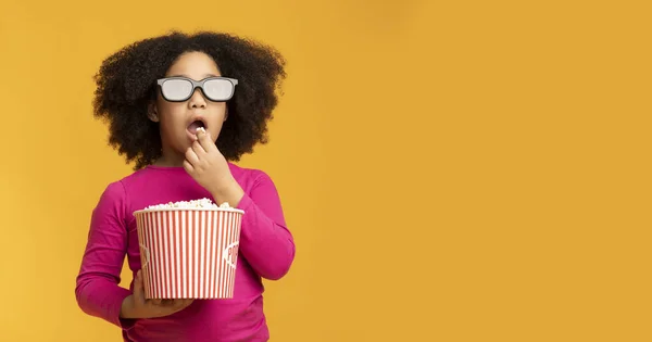 Cinema infantil. Menina negra vestindo óculos 3D e comendo pipocas — Fotografia de Stock