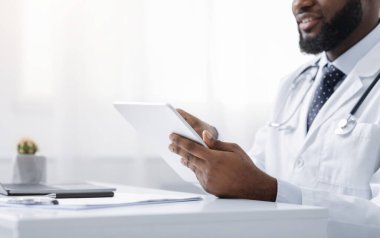 Dijital tablet kullanan Afrikalı Amerikalı doktor, internette çalışıyor.