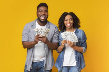 Mutlu milenyum çifti bol paralı poz veriyor, dolar hayranlarıyla takılıyor, boş alanlı turuncu panorama arka planı var.