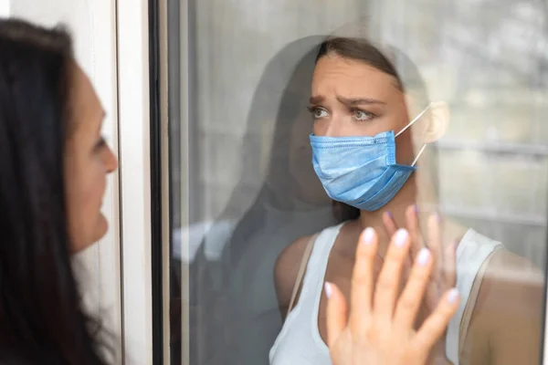 Zieke vrouw in masker aanraken moeders hand door de deur Indoor — Stockfoto