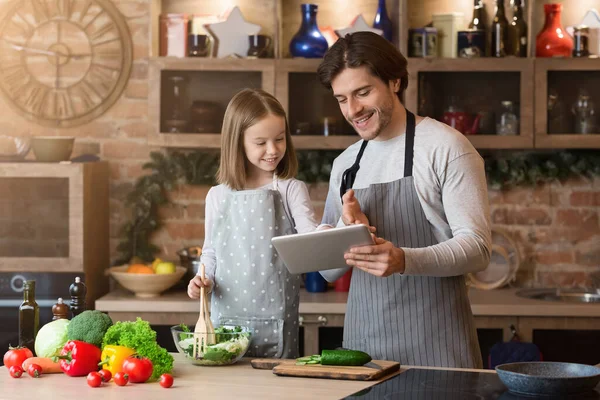 Recept alkalmazás. Apa és kislánya digitális táblagépet használ a konyhában — Stock Fotó