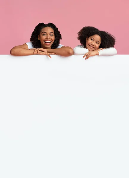 Söt liten svart flicka och hennes mamma lutar sig på vit bräda — Stockfoto