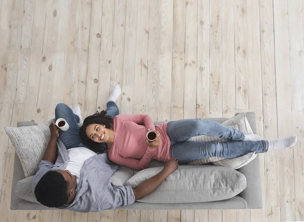 Isolamento em casa. Sorrindo casal preto relaxante com café, vista superior — Fotografia de Stock