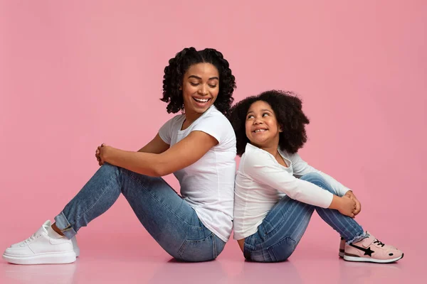 Zwart mam en kleine dochter zitten op vloer rug naar rug — Stockfoto