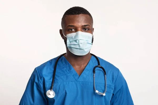 Retrato de médico negro confiado en máscara facial sobre blanco —  Fotos de Stock