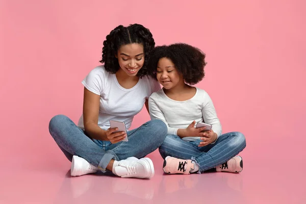 Sonriente madre negra enseñando a su hijita a usar Smartphone — Foto de Stock