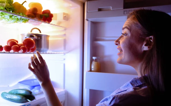 Millennial dona de casa escolher vegetais para lanche na geladeira — Fotografia de Stock