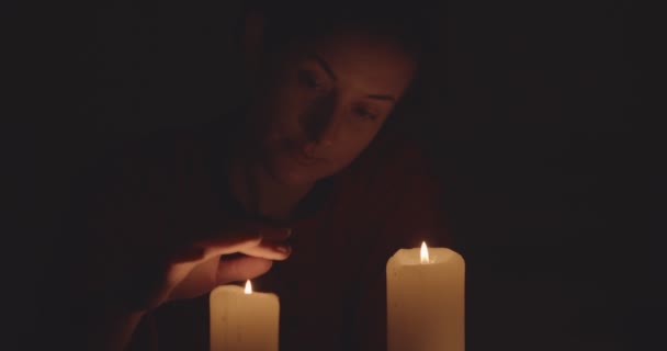 Frau berührt auf mysteriöse Weise brennende Kerzen in der Dunkelheit — Stockvideo
