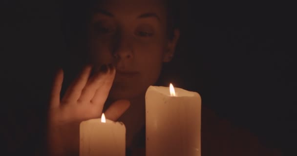 若い女性がキャンドルに触れる炎暗闇の中で — ストック動画