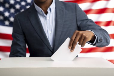 Afro-Amerikalı adam oy pusulasının üzerinde zarfı elinde tutuyor