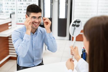 Optometrist düzeltici gözlük seçmesine yardım ediyor.