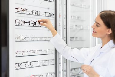 Kadın optometrist istemcinin gözlük seçmesine yardım ediyor