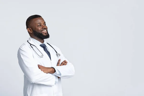 身穿白色制服的快乐的非洲医生看着复印空间 — 图库照片