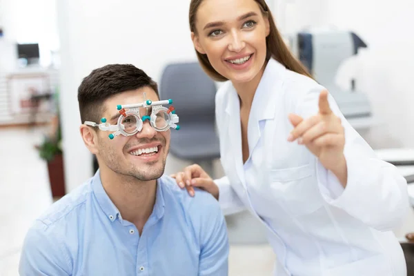 Optometrist die het gezichtsvermogen van patiënten controleert met onderzoeksframe — Stockfoto