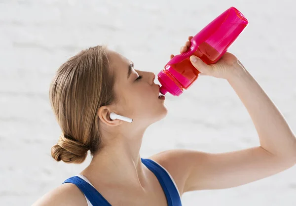 Hidratación durante el entrenamiento. Milenial atleta beber agua de la botella de deportes en el interior — Foto de Stock