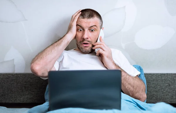 Homme parlant sur le téléphone cellulaire naviguant sur Internet au lit à la maison — Photo
