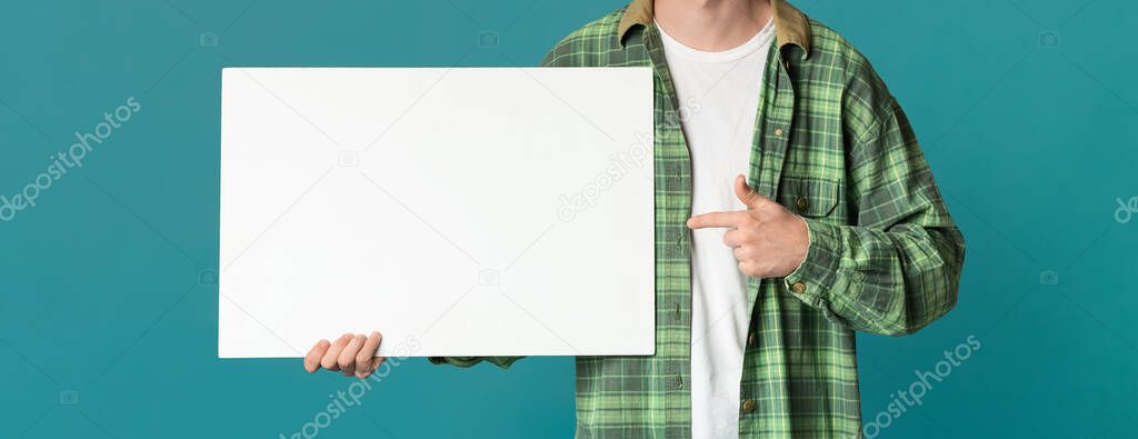 Unrecognizable young man pointing at empty sheet of paper, turquoise background. Empty space. Panorama