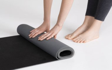 Antrenmandan sonra yoga minderini yuvarlayan, beyaz stüdyo geçmişi olan tanınmamış genç kız.